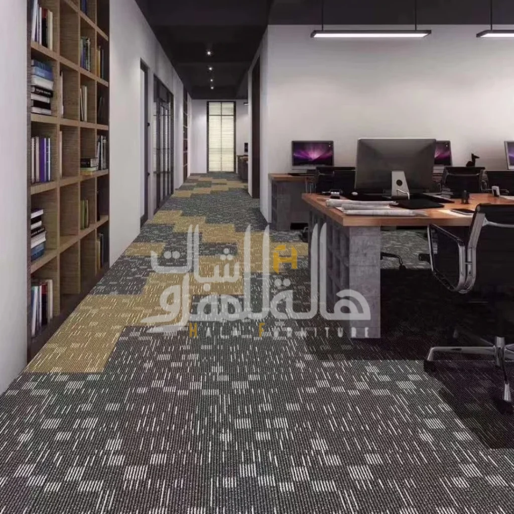 Office Carpets 17 Modern office space featuring modular carpet tiles in charcoal grey and gold patterns, with workstations and wooden bookshelves.